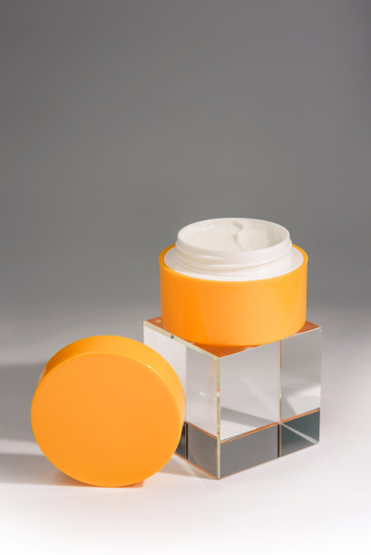 打开一罐化妆品霜和一个玻璃立方体在灰色和白色的背景与复制空间。图片下载