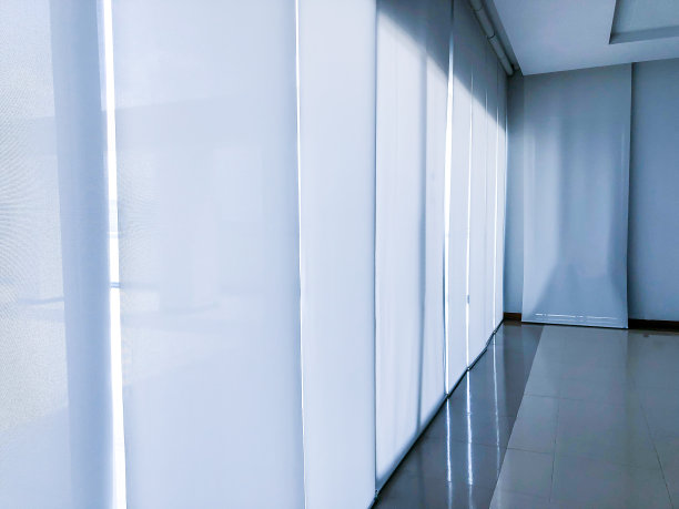 早晨，办公室里的一幅巨大的白色窗帘挡住了阳光照进大楼。图片下载