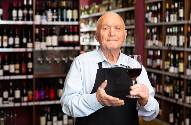 自信的老年男性酿酒师邀请到酒庄，提供一杯葡萄酒供品尝图片下载