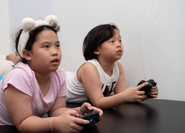 亚洲儿童在家里通过控制器玩电子游戏图片下载