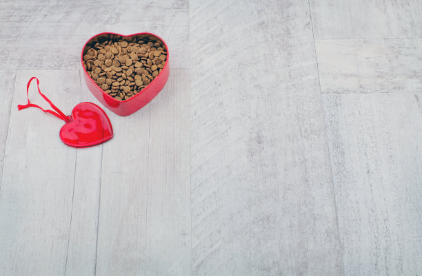 心形的碗与宠物的食物和红心玩具在木制的背景。带着爱动物的概念。本空间图片下载