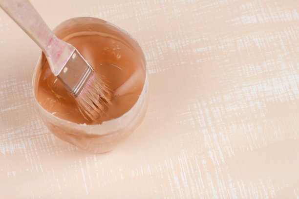 托盘上有米色油漆和油漆刷的残留物。在白色和米色的表面上。图片下载