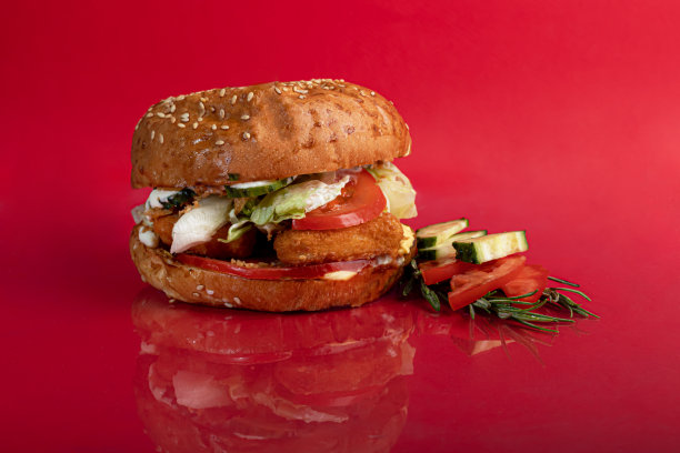 美味的烤汉堡配番茄肉片，芝士，黄瓜和沙拉。在红色背景上。图片下载