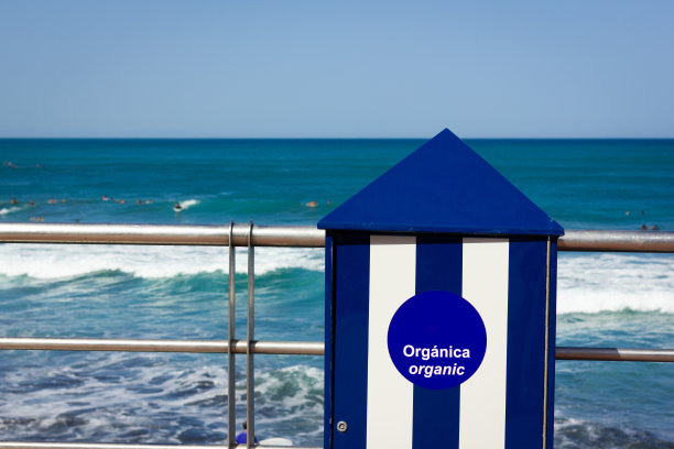 蓝色和白色条纹的有机垃圾桶在海边图片下载