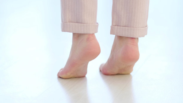 侧面近距离观看无法辨认的女人脚腿，赤脚的女孩站在室内的现代家庭享受温暖的木地板。软焦点图片下载