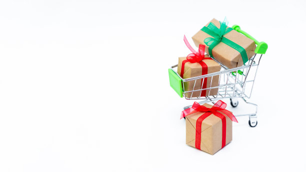 白色背景上有礼品盒的小购物车。情人节，圣诞节和生日的礼物。网上购物。新年假期销售和折扣。零售和批发采购。图片下载