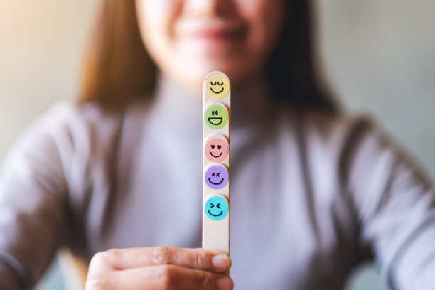 一个女人拿着彩色的手在木棒上画着幸福的表情图片下载