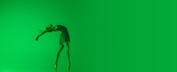 年轻优雅的芭蕾舞演员孤立在霓虹灯下渐变色的绿色演播室背景。运动中的艺术图片下载