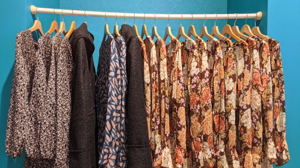 在服装女孩时装店，女人们把衣服挂在衣架上图片下载
