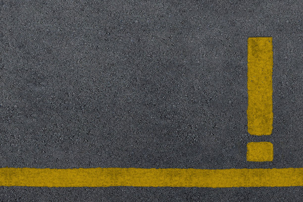 黄色感叹号标志画在沥青路面上图片下载