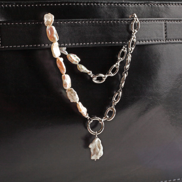 女人的银色巴洛克珍珠项链垂饰在男性的黑色皮箱图片下载