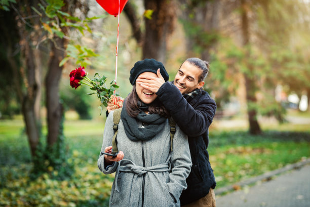年轻男子惊讶的女人与玫瑰花束和气球库存照片。日期/爱情/圣瓦伦丁节概念。图片下载