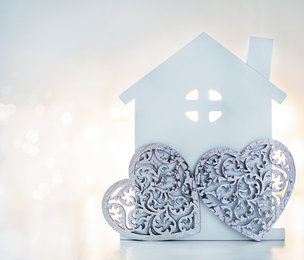 一个房子模型和灰色的心为家庭背景与光散景。家庭和情人节的概念。图片下载