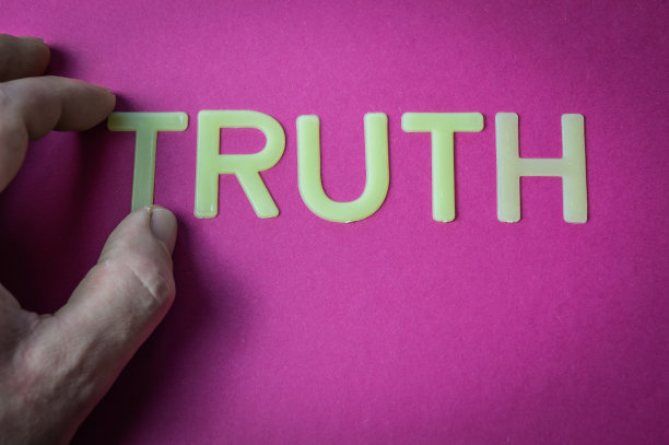 人的手拿着写有塑料字母的单词真理在亮粉色的纸背景上，概念图片下载