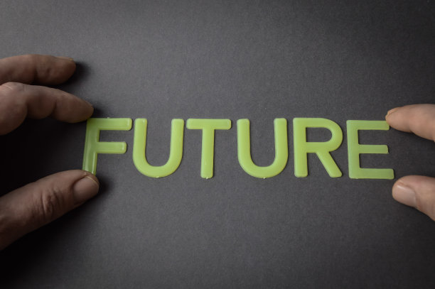 人类的手指在深灰色的纸上用塑料字母写着“未来”，概念图片下载