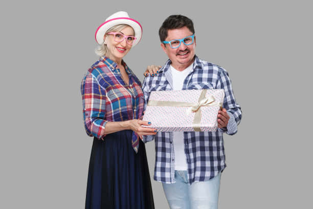 一对积极的朋友，成年男人和女人在休闲格子衬衫站在一起拿着礼物礼盒，牙齿微笑和看。图片下载