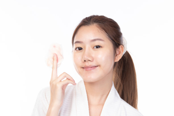 迷人的美丽年轻的亚洲女子清洁皮肤与卸妆棉在白色的背景。图片下载