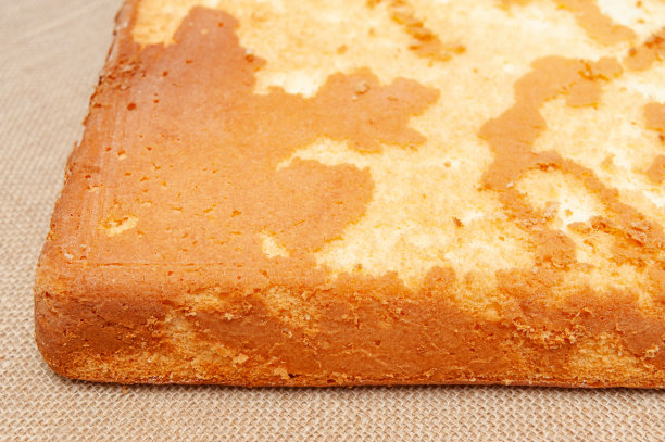 自制海绵蛋糕，葡萄牙的Pao De Lo。烤好的蛋糕面团的底部。孤立在黄麻背景上。特写镜头。水平射图片下载