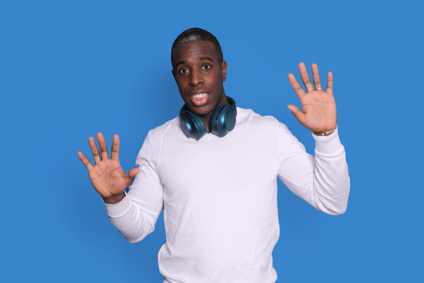 困惑的年轻非洲裔美国人在白色街道穿毛衣摆孤立的蓝色背景，举起手，显示手掌图片下载