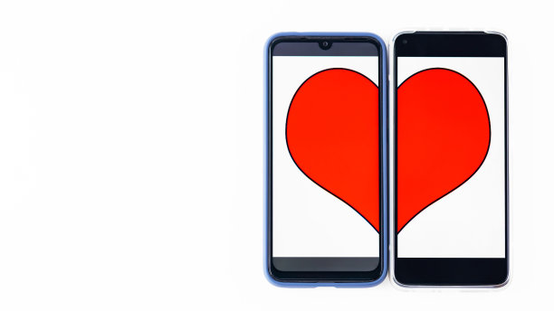 网上约会的概念。两个智能手机屏幕上的心脏的一半。白色背景上的情人节概念。副本的空间。俯视图图片下载