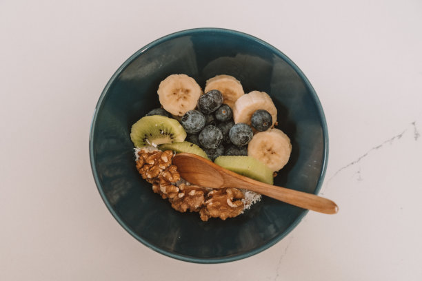 木桌上有一碗什锦麦片，里面有香蕉片、蓝莓片、猕猴桃片和草莓片。健康饮食，健康早餐节食理念图片下载
