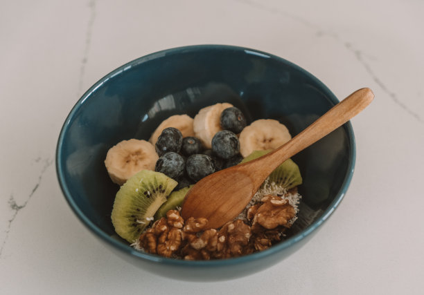 木桌上有一碗什锦麦片，里面有香蕉片、蓝莓片、猕猴桃片和草莓片。健康饮食，健康早餐节食理念图片下载