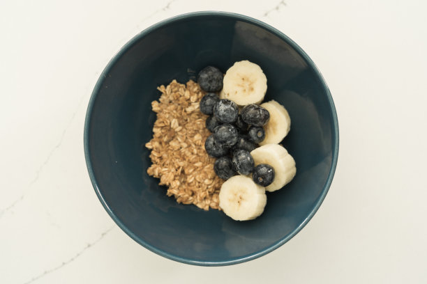木桌上有一碗什锦麦片，里面有香蕉片、蓝莓片、猕猴桃片和草莓片。健康饮食，健康早餐节食理念图片下载