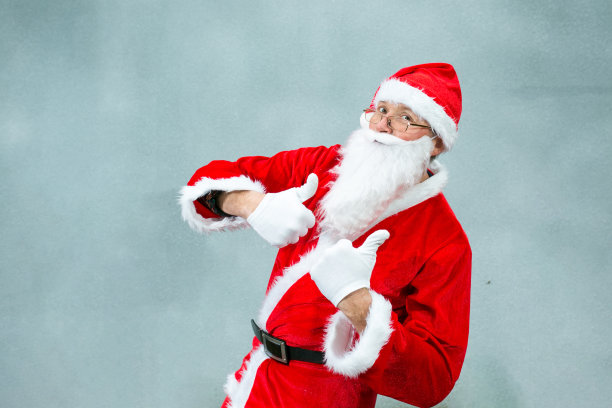 圣诞老人的肖像在一个灰色的背景。情感的概念。圣诞老人用手势表达圣诞来临的喜悦。图片下载
