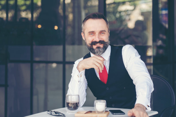 在咖啡馆喝咖啡的商人。人们英俊的看着远离街道附近的城市。图片下载