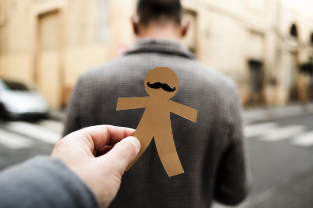 一个男人要把一个纸人娃娃粘到另一个男人身上图片下载