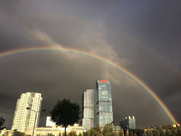 双虹反射在一个黑暗的阴天在城市的高楼大厦和摩天大楼图片下载