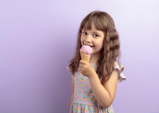 可爱的小女孩吃着美味的冰淇淋。图片下载