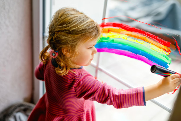 在冠状病毒大流行隔离期间，可爱的小女孩用五颜六色的窗户颜色涂着彩虹和心形。孩子们用“让我们一切都好”这句话在世界各地画彩虹图片下载
