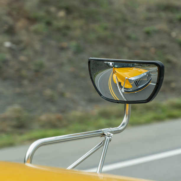 在深秋的山路上行驶的校车从后视镜中反射出来图片下载