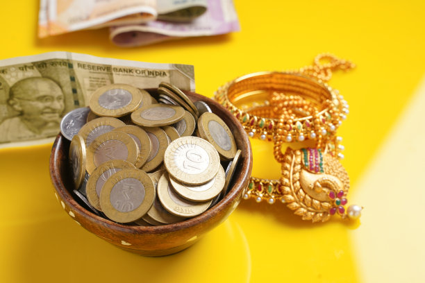 印度卢比纸币，硬币和黄金首饰上的黄色背景图片下载