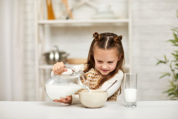 小女孩吃早餐:麦片加牛奶。图片下载