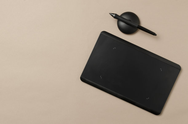 俯视图的黑色图形平板电脑与空白屏幕和笔在棕色的桌子上。空的空间图片下载
