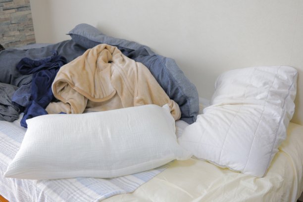床，羽绒被和枕头在一个肮脏的房间和凌乱的衣服图片下载