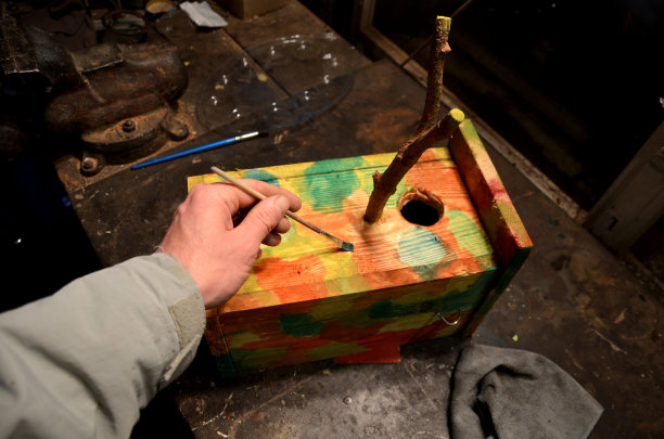 冬天养蜂，制作鸟舍。用画笔和颜料与儿童着色，我们创建颜色伪装图案根据军事设计在车库。图片下载