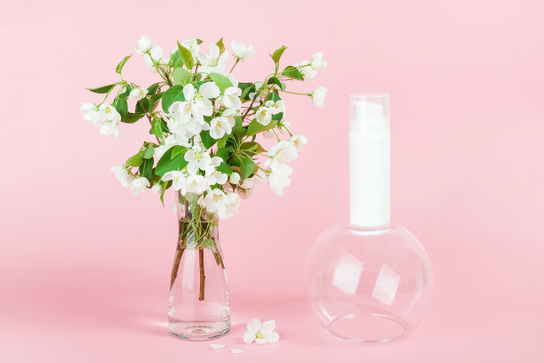 一个白色空白的化妆品管瓶和盛开的树枝在花瓶在粉红色的背景。天然有机温泉美容美容概念。前视图图片下载