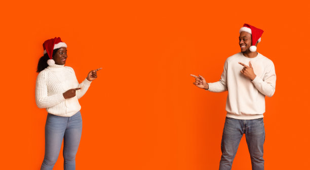 圣诞促销。幸福的黑人夫妇指着中间的拷贝空间图片下载