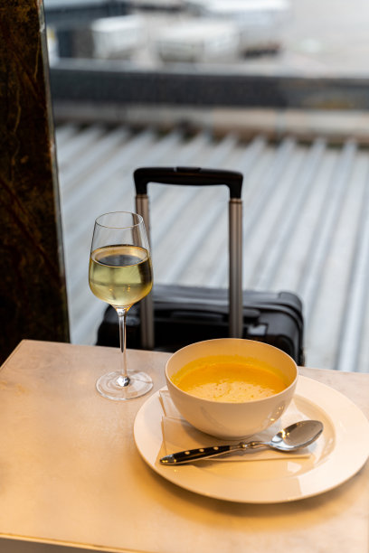 在机场，一杯白葡萄酒，一碗汤和一件黑色的现代行李图片下载