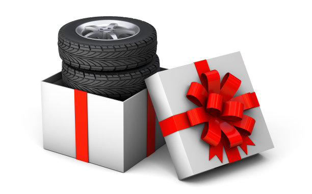 轮胎是礼物。一套四个轮胎在一个礼品盒用一个红色的礼品丝带和一个蝴蝶结。孤立在白色背景上。三维渲染图片下载