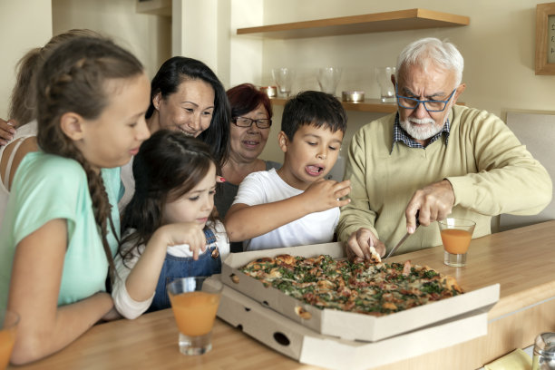 多代同堂的家庭在厨房岛吃美味的披萨。图片下载