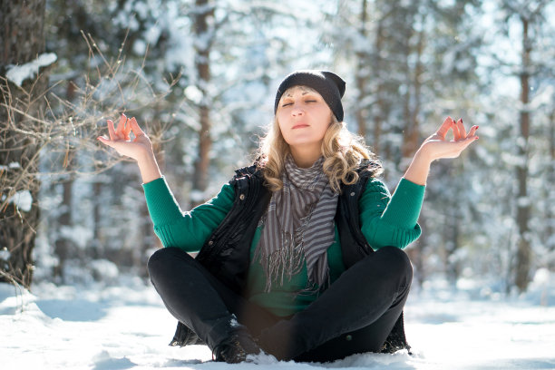 在白雪覆盖的公园里做瑜伽的女人。图片下载