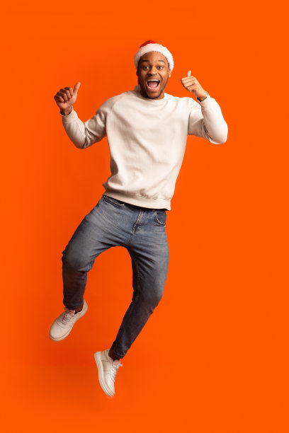 兴奋的黑色圣诞老人在圣诞帽跳和手势拇指向上图片下载