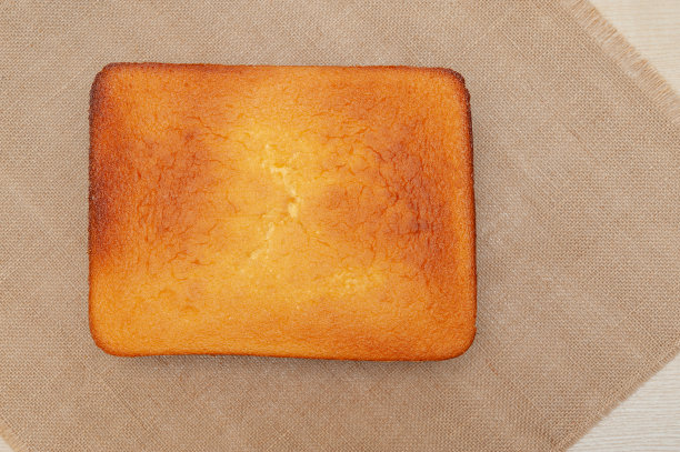 自制海绵蛋糕，葡萄牙语Pão de Ló。在烤好的蛋糕面团上面。孤立在黄麻背景上。前视图。本空间图片下载