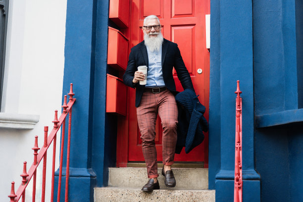 时髦的老男人一边喝着咖啡一边走出门，背景是家的门——注意脸图片下载