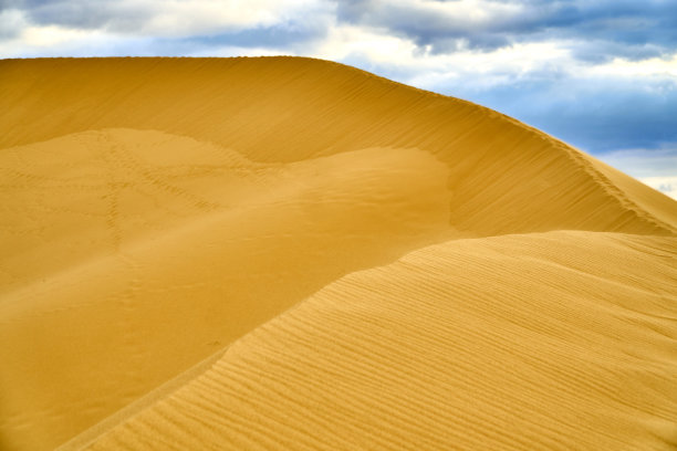 沙漠。沙丘。蓝天白云。鸟在日落时分。山脉。天空。图片下载