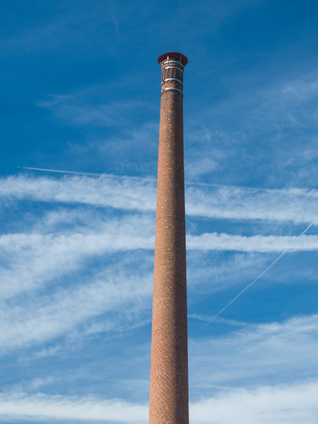 古老的高大的砖砌烟囱。天空中有细长的云。垂直图片下载
